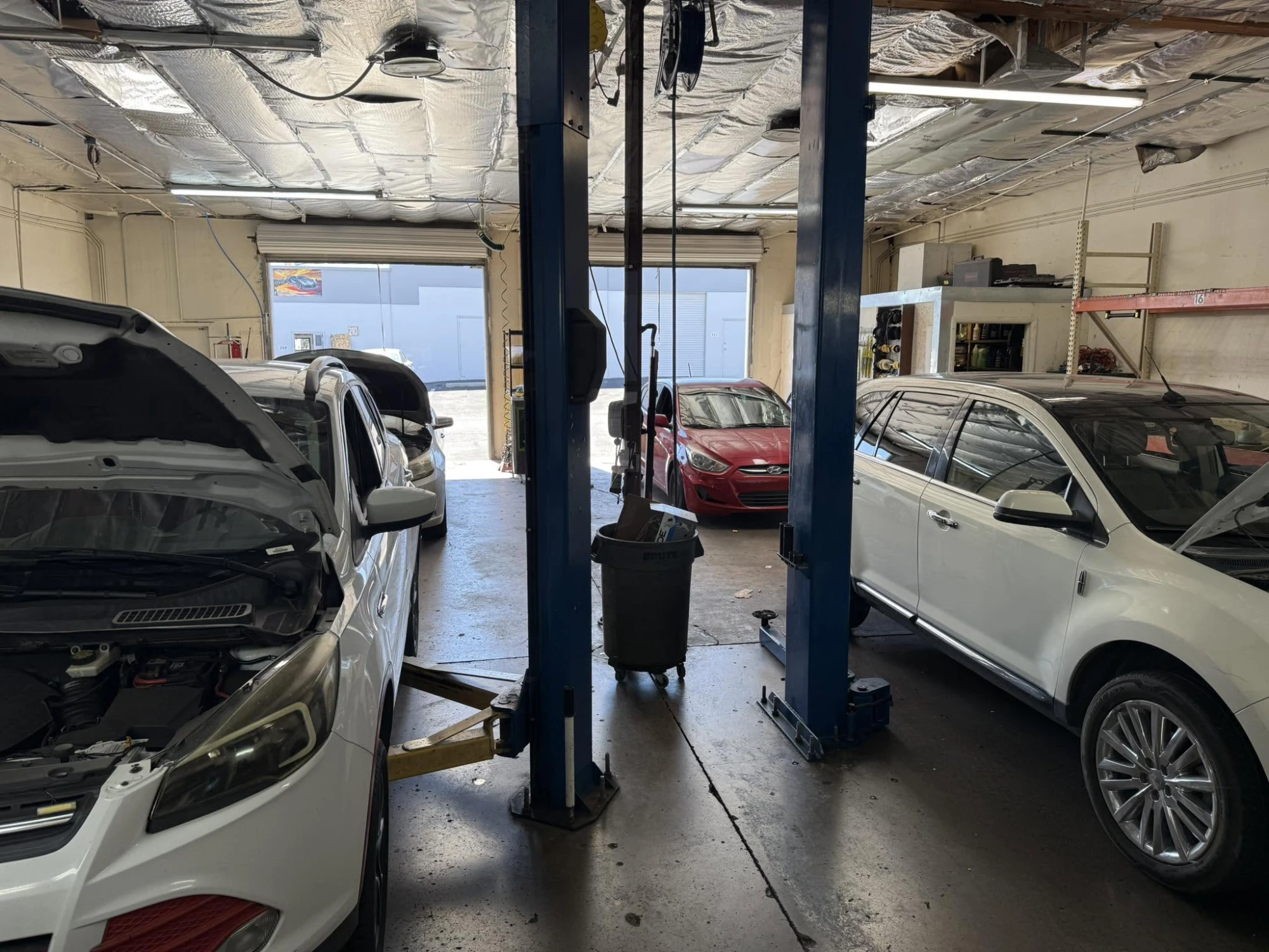Inside the Cousin's Wrenches shop — two-post lifts and customer vehicles in the bays